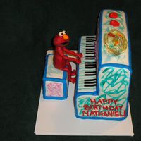 Elmo's World Piano Piano and stool are cake covered in fondant. Elmo is candy clay and fondant. Fish bowl is first attempt at poured sugar.