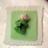 Baby 3-D out of fondant, of a baby clasping a bottle on his blankie. I made this for a baby shower cake. Baby is handmade, without a mold.