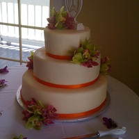 Orchids 3 tier fondant covered wedding cake adorned with live cymbidium orchids and orange satin ribbon