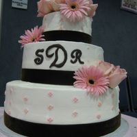 Brown And Pink Wedding Three tier, bc decorated with pink edible pearls, dark brown velvet ribbon, and fresh roses and gerber daisies. The monogram was piped with...