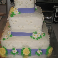 Daisies And Yellow Roses Three tiered square wedding cake with daisies and yellow roses.