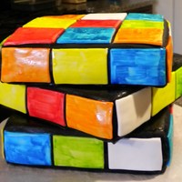Rubik's Cube Cake: 3 - 8 inch squares covered in black fondant. Square tiles made from fondant, and hand-painted w/ food coloring. This was fun to make...