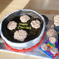 Latkes In A Pan 12" round cake shaped into frying pan. Donut handles. Yellow gel for oil. Latkes are RKT with chocolate added in. Spatula and napkin...