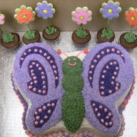 Butterfly With Flowers buterfly cake made with wilton cake pan decorated with buttercream and the flowers are mini cupcakes with flower cookies!