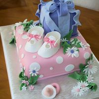 Booties For Baby This in baby shower cake, tiers made to look like gifts boxes with baby Booties, daisies and a pacifier made out of fondant.