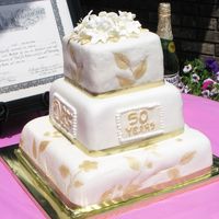 50Th Wedding Anniversary First cake for an event. I gave it to them as a gift to practice. White fondant with gold accents. Any suggestions on how to improve are...