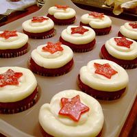 Red Velvet Holiday Cupcakes Red velvet cupcakes with cream cheese buttercream. Topped off with a hand painted red gumpaste star sprinkled with edible snow glitter.
