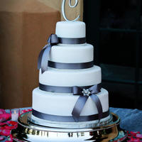 Breann 4 tier white fondant covered with pearl sheen, charcoal grey ribbon, bling band, ribbon bows with bling broaches. Flavors included...
