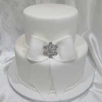 Pure Elegance Made for a bridal show. 2 tier 6 and 9 inches, fondant covered and sprayed with pearl sheen. Fondant bow and bling broach.