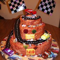 Disney Cars Cake Stacked cake covered with fondant. Fondant road, chocolate rocks and toy Disney Cars characters.