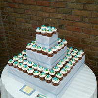 Baby Shower Cupcake Display carrot cupcakes with cream cheese frosting and sugar flowers on top.