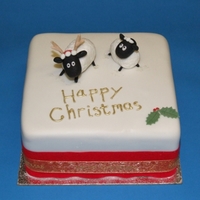 Sheep Christmas Cake Fondant covered miniature fruit cake with antler-wearing sheep toppers made from sugar paste
