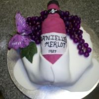 Wine Bottle Made for a 21st birthday. White fondant draped over the sides, fake grapes and butterfly. The bottle is rice krispies covered in fondant.