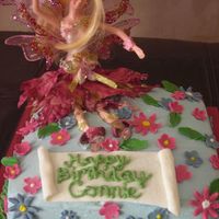 Fairy Land Fairy sitting in a bed of fondant flowers on top of buttercream with buttercream grass border.