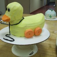 Toy Duck This is a duck that I carved out of pound cake and covered with buttercream icing, gum paste wheels, and choco-pan string