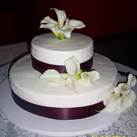 2 Tier Wedding Cake With Calla Lillies My first wedding cake. Definitely not perfect, but the bride and groom loved it. All buttercream with scroll work on each tier. Ribbon...