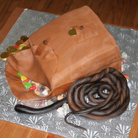 Indiana Jones Satchel And Whip Chocolate cake with buttercream filling. Fondant covered, fondant whip and candy accents.