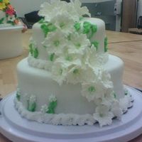 First Tiered Cake, Easter Lily Cake Lillies made with royal icing and 2 different lily nails. 9x3 round pan, 6x2 roundpan, doubled. Covered in buttercream icing and fondant.