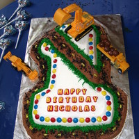 1St Birthday Construction Cake #1 character pan covered with buttercream frosting, crumbled oreo cookies, M&M's, and whoppers.