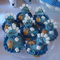 "its A Boy" Baby Shower Cupcakes cut adorable baby shower cupcakes. they are blue since it is for a boy. teddy graham bears, marshmallow bottles, blue melted chocolate pins...