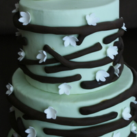 Birds Two tier cake green cake with large brown twigs, small white flowers, and white love bird topper.