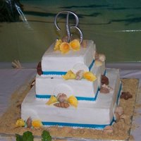 Beach Themed Chocolate and vanilla cake covered in buttercream and ribbon. The seashells are candymelts, the sand dollars are fondant, and the calla...