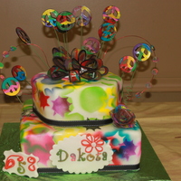 Groovy Tie Dye Cake chocolate and vanilla bean cake with vanilla bean buttercream icing covered in air brushed MMF. All accents are fondant. Inside was tie dye...