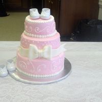 Pink Baby Shower Cake With Booties Covered in buttercream with fondant bow.