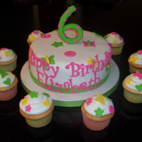 Elizabeths Cake 8 inch round covered in fondant with fondant details and 6 on top. Cupcakes iced in butter cream with smaller fondant cutouts to match.