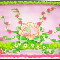 A Budding Baby Shower sheet cake frosted in buttercream and airbrushed with a touch of purple. Green leaves and vines tipped on with accenting flowers to...