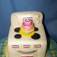 Stove Or Oven White cake sculpted to look like child's oven with fondant birthday cake on top. Oven window was made by melting LifeSavers.