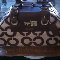 Coach Purse Cake coach purse cake. All details are fondant. Handles were suppose to be standing up but they did not dry in time and they broke.