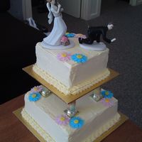 My First Wedding Cake Two-tiered pillared wedding cake with humourous fishing cake topper, edible daisies, cream cheese icing. The cake is triple layer mango...