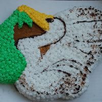 Stork (Character Pan Cake) Stork is holding a green blanket. Yellow cake covered with butter cream. I have used one raisin for the eye and have tried to define the...