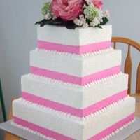 Lace Wedding Cake 4 tiered cake in buttercream with pink ribbon and lace on all tiers. The top is a floral arrangement