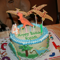 Dinosaur Cake Chocolate chip cake filled with cookie dough and Bettercream. Covered with vanilla frosting and sugar cookies with royal icing details.