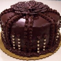 000A051Zdnp.jpg 8" chocolate cake filled and frosted w/chocolate whip topping, covered in chocolate ganache, decorated with chocolate fudge frosting...