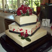 Black, Red, Cream, Wedding Cake Buttercream frosting cake with ribbon around bottom and red piping gel hearts and topper real red roses. Buttercream is not the best for...