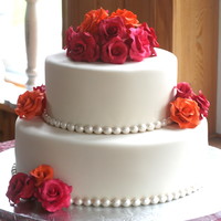 Orange, Red And Pink Rose Wedding Cake Cake covered in ivory fondant, pearl molds, gumpaste roses in red, orange and pink. TFL!