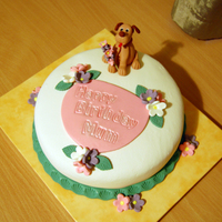 Birthday Cake With A Dog Chocolate cake, covered with fondant. Puppy and flowers are made from gumpaste.