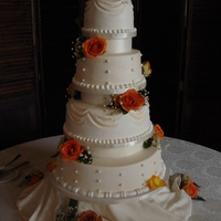 Draped Buttercream Wedding Cake Four tier ivory draped buttercream with fondant pearls. Fresh flowers.