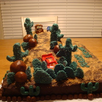 Lightening Mcqueen Lightening McQueen slides into cactus. The cake is white almond and iced in chocolate buttercream. The cactus and boulders are candy clay...