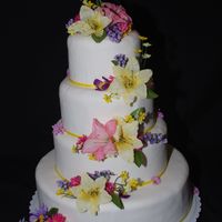 Easter Wedding This a fondant covered cake with yellow and pink lilies and misc colored flowers cascading down the cake.
