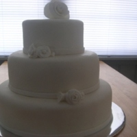 White Fondant With White Rose Wedding Cake This is a white fondant wedding cake with white gumpaste roses.