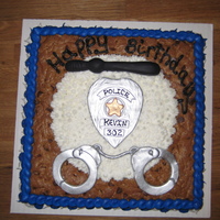 Cookie Cake--Police 2 inch high chocolate cookie cake. Lots of fun. Buttercream frosting and fondant badge, hand cuffs and baton.