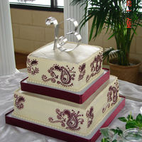 Paisley Cake Two tier square italian cream cake with cream cheese icing. Hand piped paisley design in marroon with non-edible B cake topper.