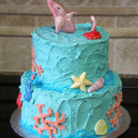 Sea Themed Cake This sea themed cake has a pink dolphin jumping out of the top, crabs, seahorses, shells and coral.