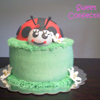 Ladybug Cake Chocolate cake with chocolate ganache filling. Bottom tier is covered in buttercream with royal icing lilies. Ladybug is covered in fondant...