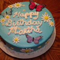 Daisies And Butterflies Round cake with buttercream icing, fondant daisies, and "real" butterflies.
