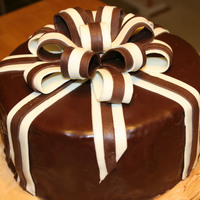 Surprise!! Happy Birthday Donnie! White chocolate cake, covered in a poured ganche, and chocolate clay ribbons.The hardest part is getting the ganche to pour properly.